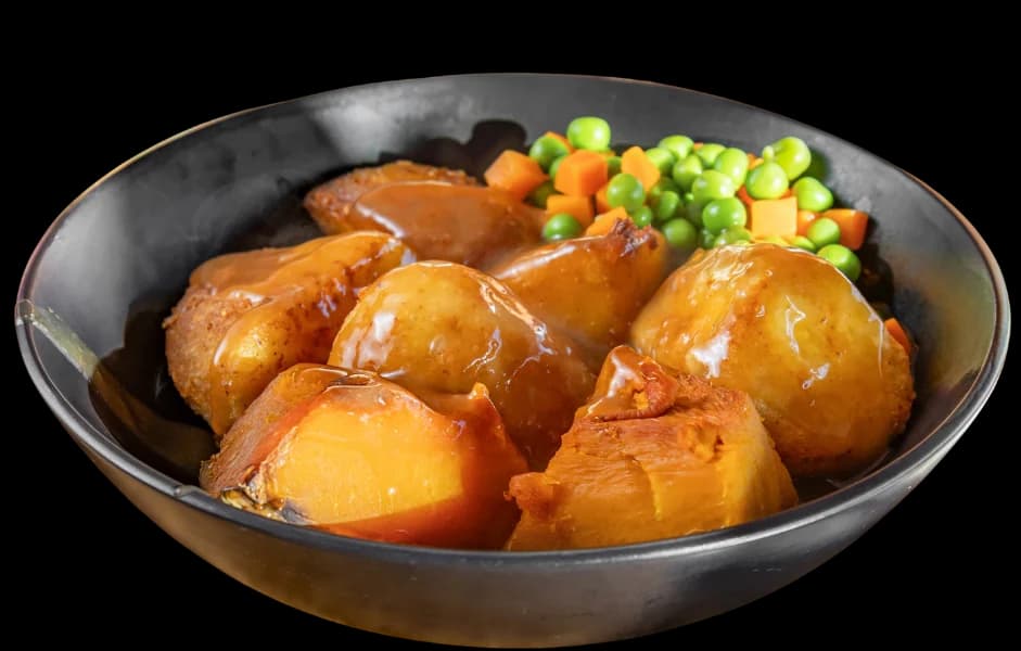 A bowl of roast potatoes, pumpkin, kūmara, peas and carrots in gravy